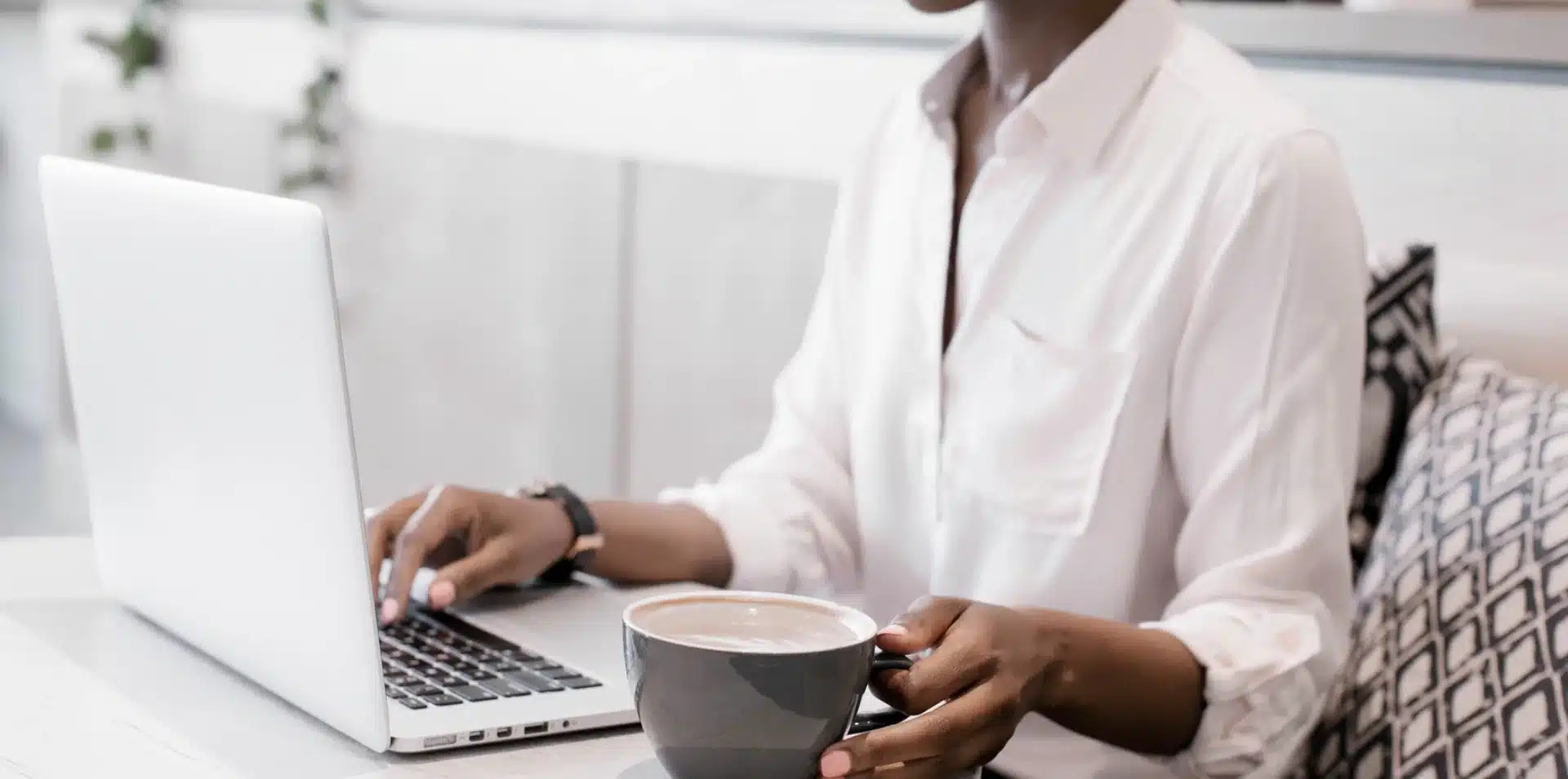 AI Search Visibility for Local Businesses Business owner working on a laptop with coffee at a bright desk.
